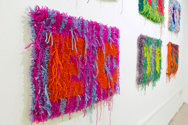 Close up image of multi-colour rectangular carpet wall work with the letters 'E' and 'C'