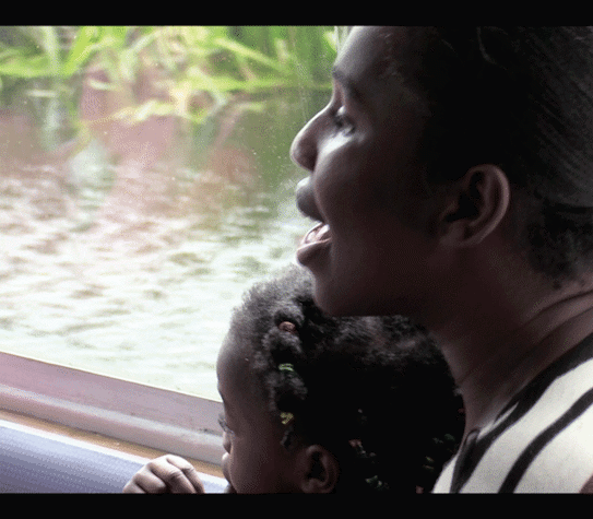 Film still of an adult and child looking out of a boat window