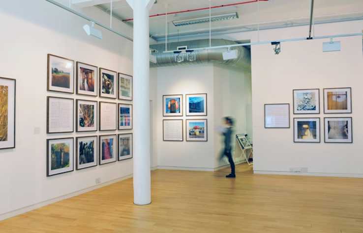 installation view of a gallery space with multiple square framed photographs on the walls.