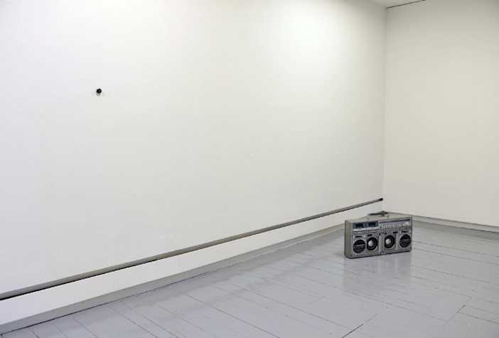 empty white room with a silver boombox on the floor