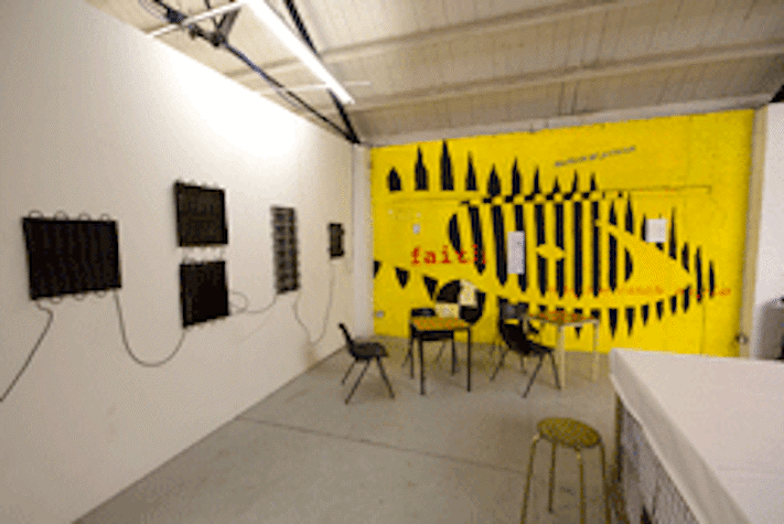 Gallery installation, mounted screens on wall, chairs and tables, graphic eye design