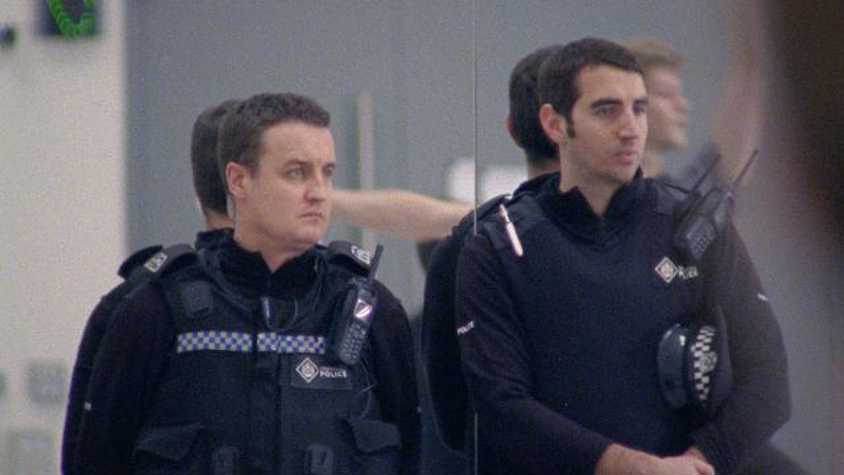 film still of two police officers watching a rehearsal in a dance studio