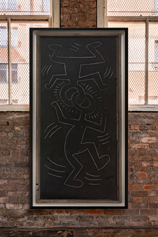 A large black board with white illustrations is displayed on a brick wall. The illustrations are of two human figures connected at the head.