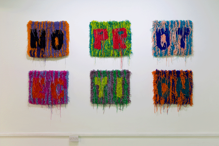Image of six small multi-colour rectangular carpets in a grid of two rows of three. the carpets read the letters 'N, O'; 'P, R'; 'O, T'; 'E, C'; 'T, I'; 'O, N'