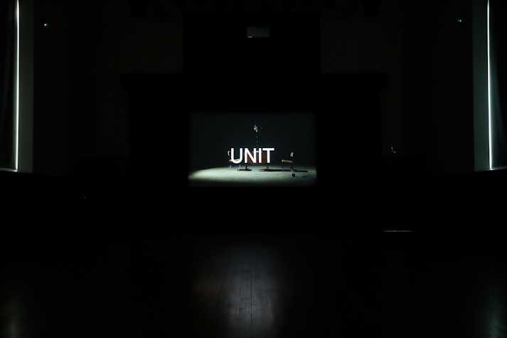 Screen showing image of film with chairs and the word UNIT