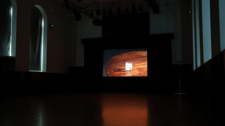 Screen showing image of film with a glass on a wooden table