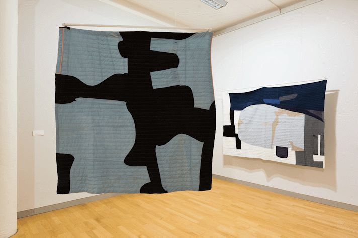 installation view image of large scale quilt hangings with abstract cut out shapes