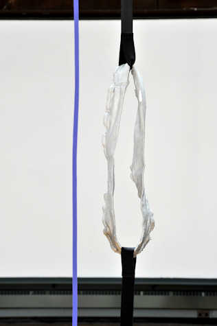 on the left of the frame is a single blue line. right of it there is a vertical black strap with a silver circular looped strap held between