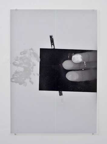 black and white image with a white background, a black rectangular and three fingers pressed against something.
