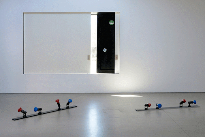 White-walled gallery with sculptural works including light fixings laid out on the floor