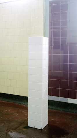white tiled plinth infront of a tiled wall
