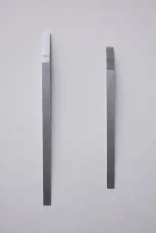 two small abstract aluminium sculptures are mounted on a white wall. They sit parallel to one another and resemble an elongated ramp leading to a flight of stairs.