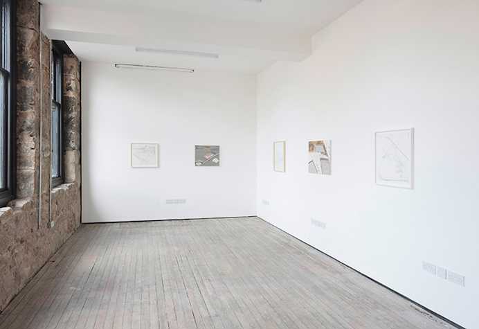 Installation view of exhibition in a white walled gallery with small works visible on the wall