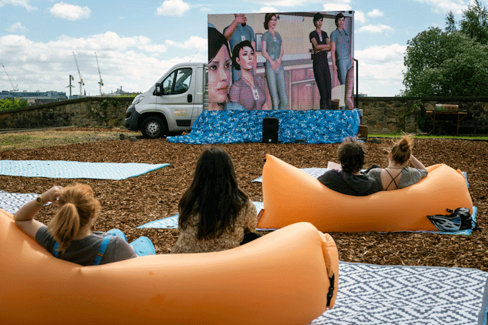 A large screen on the back of a truck shows animated NHS workers