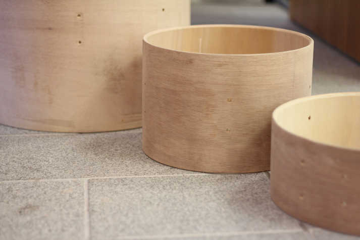 three plywood cylinders of increasing heights in a row on the floor.