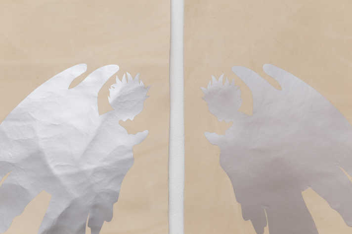 2 silver cut out silhouette of angels in mirror image on brown paper.