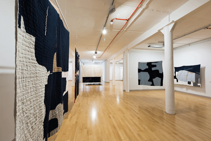 installation view image of large scale quilt hangings with abstract cut out shapes