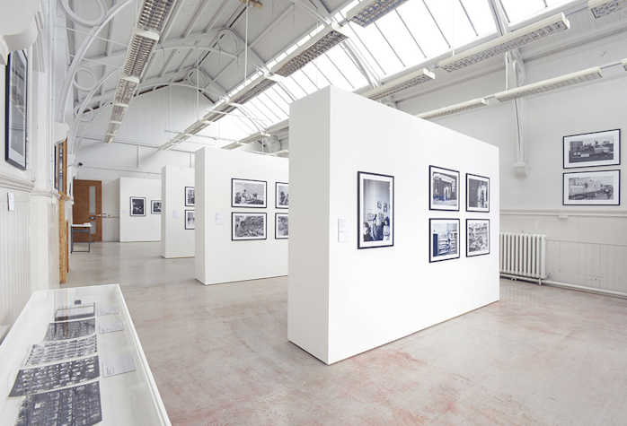 Framed photographs are displayed on white walls in a light and airy space.