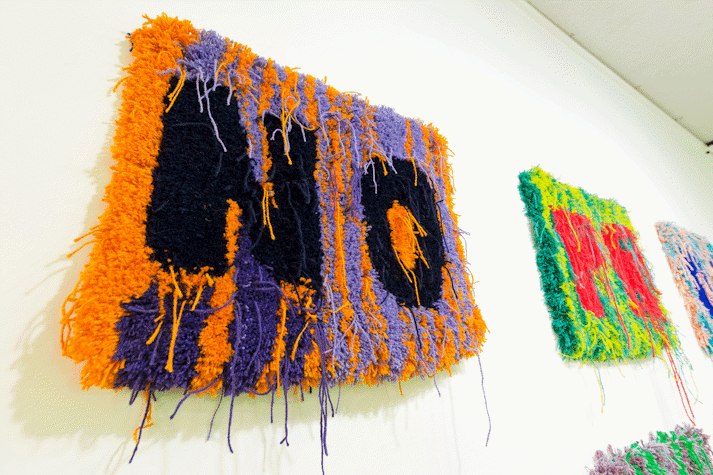 Close up image of multi-colour rectangular carpet wall work with the letters 'N' and 'O'