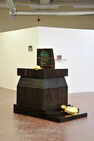 ebony wood scultpure with gold details, and laser lines crossing it. there is a blue and green circle drawn on the top of the structure