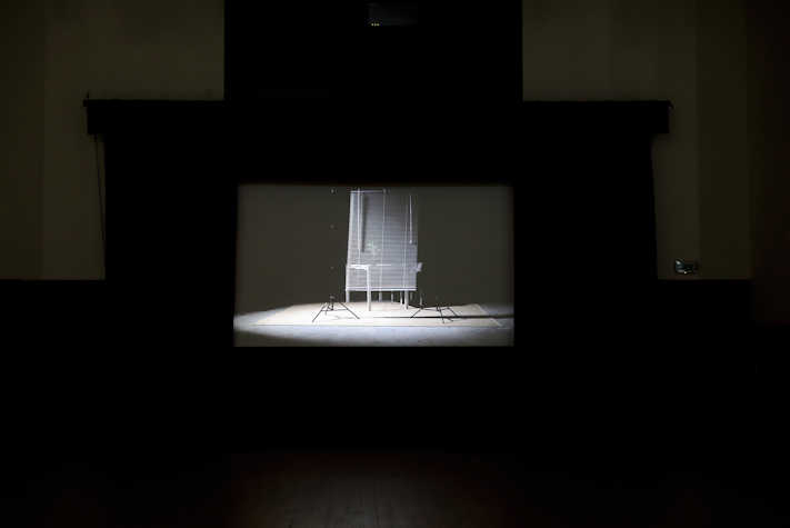 Screen showing image of film with a white table, plant and blind