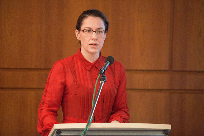 A woman is standing at a podium with a microphone in front of her.