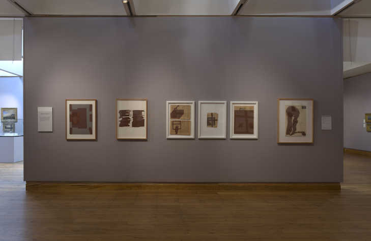 a row of framed works on a wall.