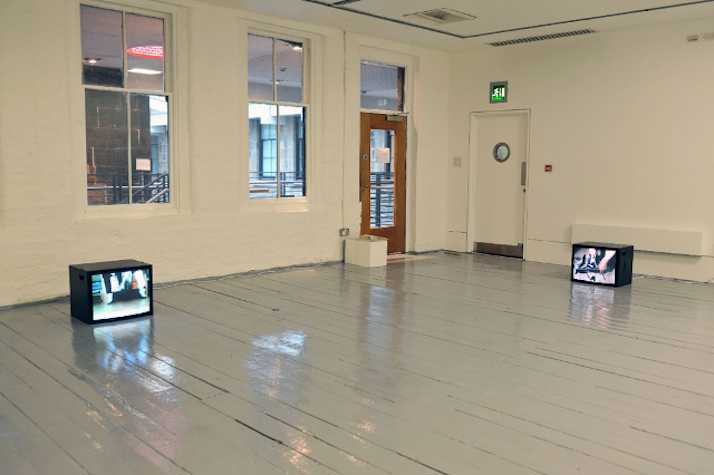 two video monitors on the floor in an otherwise empty room
