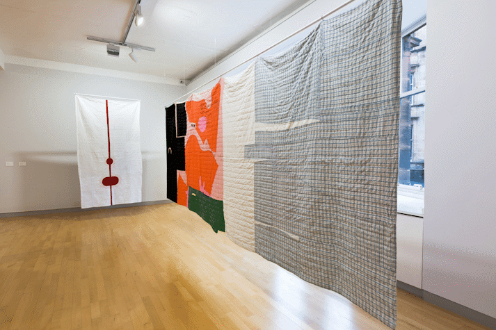 installation view image of large scale quilt hangings with abstract cut out shapes