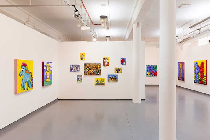 Colourful artworks are displayed on white walls in a gallery space.