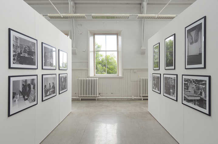 Framed photographs are displayed on two parallel walls. Between these is a window.