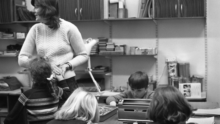 A black and white photograph or a woman in a class room