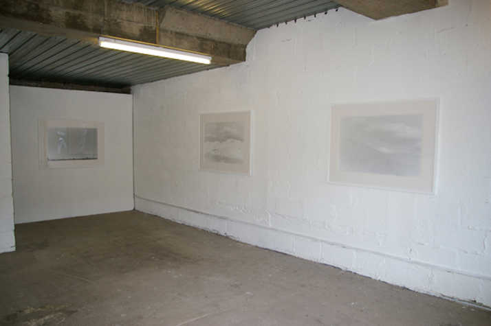gallery space with white walls. three low contrast black and white images are hung next to each other.