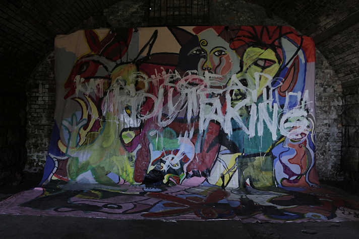 Gallery installation, hung painted fabric, splashes of colour, the bricked arch way in view