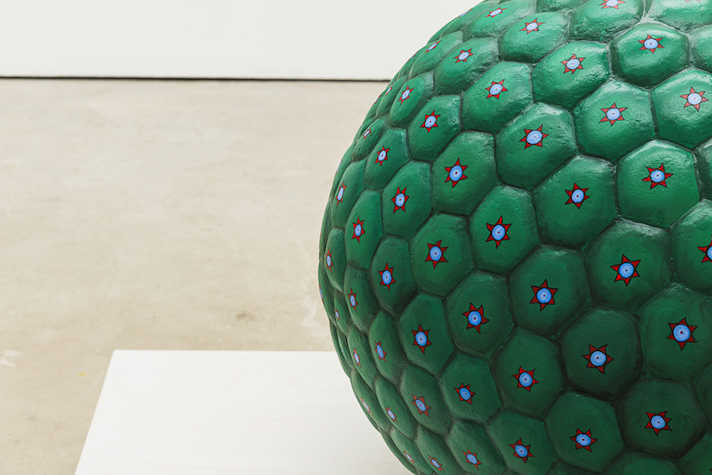 A close up of a large green sphere. There are small suns decorating the sphere in a pattern.