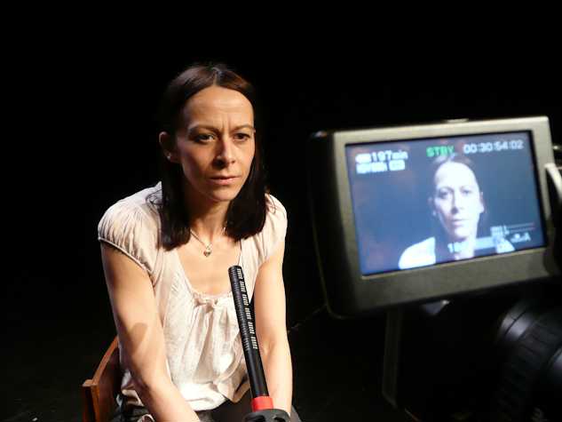 person sat in front of a microphone and video camera. you can see the screen of the video camera.