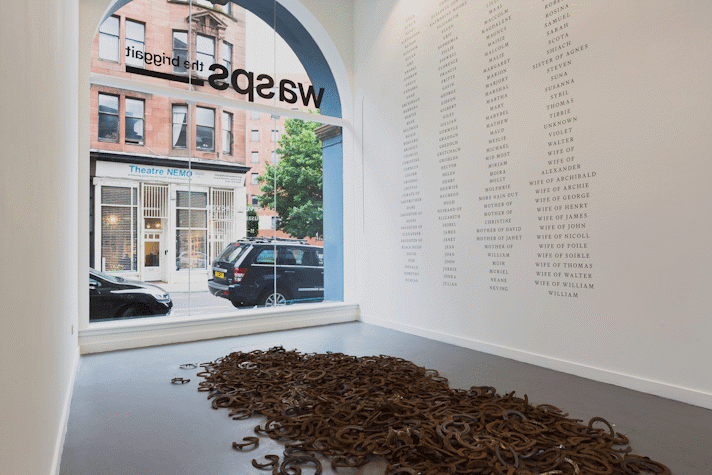 a pile of horseshoes on a gre floor. in the background is white wall with columns of black text
