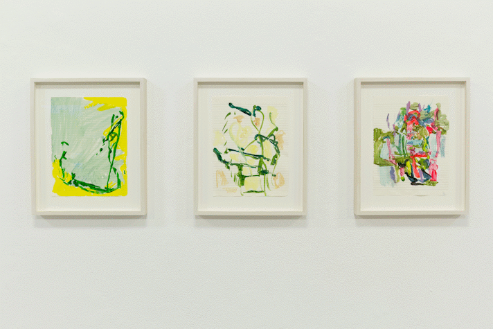 three abstract paintings on lined notebook paper hang in white stained wooden frames on a white wall