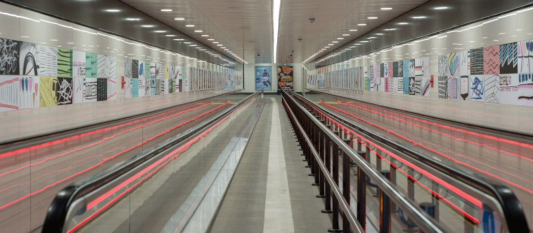 Two moving walkways with neon pink lights in Buchanan Street subway station. Artworks in the walls, fitted to the tiles.