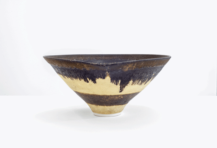 A painted ceramic bowl, with gold, blue and black paint.