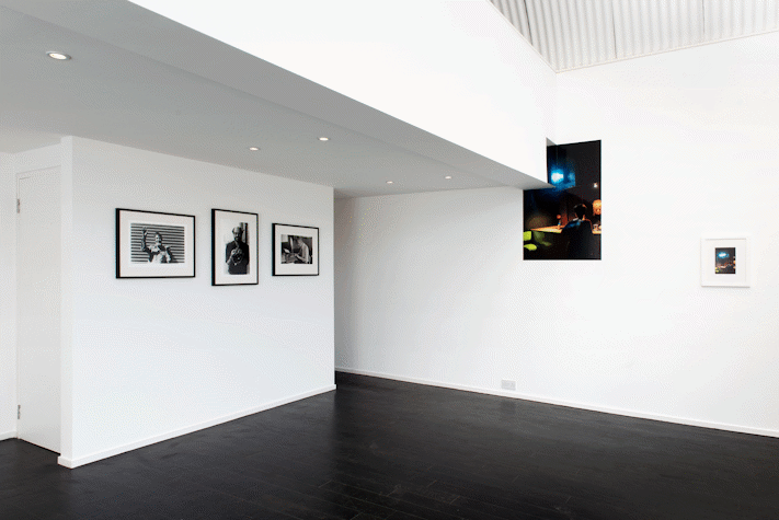 A white-walled exhibitions spaces with photographs on the floor