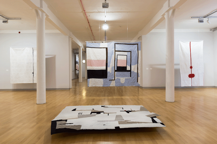 installation view image of large scale quilt hangings with abstract cut out shapes