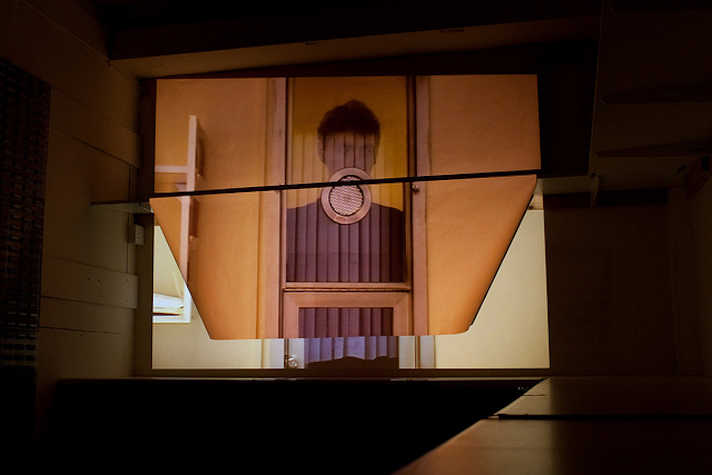 Art installation with a projected image of an illustrated person partially obscured behind a door