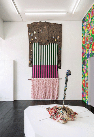 The image shows fabric artworks hung on the wall and a sculpture of tangled threads