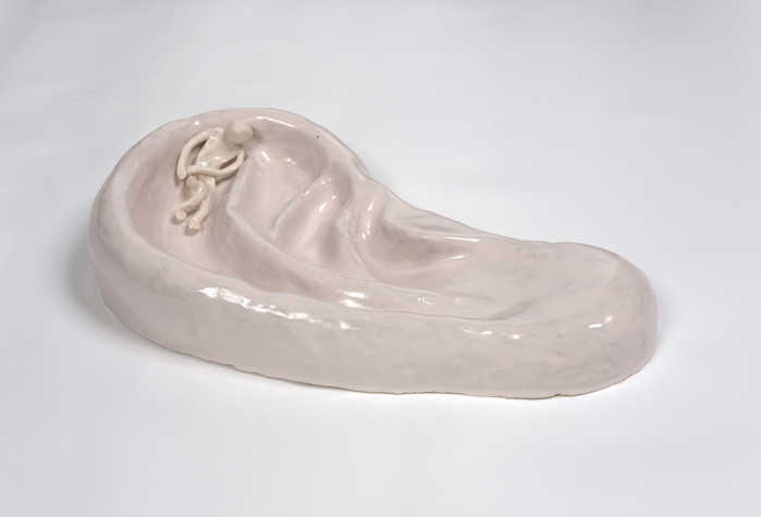 ceramic sculpture of an ear with a small implied person curled up in one of the folds