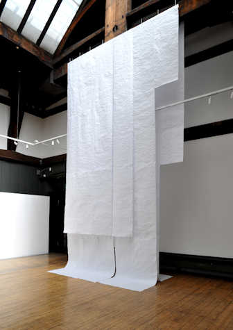 white sheets of fabric hanging from a wood beamed ceiling
