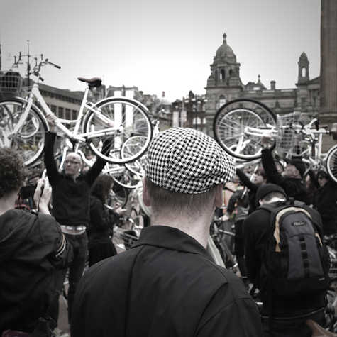 a group of people outside, holding up bicycles in the air