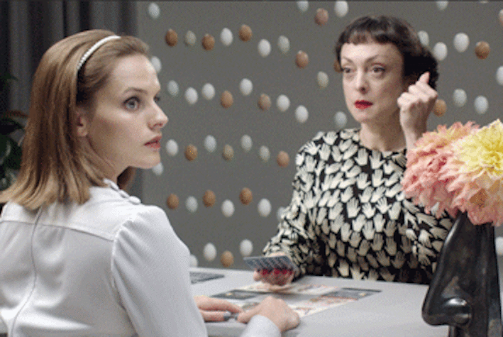 Installation shot showing film still of two women and a vase of flowers