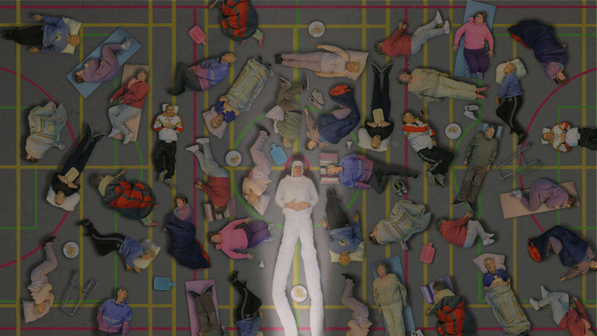 On a floor that looks like a marked basketball court, there are multiple older people lying down and asleep in different positions around a man with extremely long legs, in all white, with a spotlight on him. There are plates of food, and random home objects surrounding the people. Their clothes and blankets are colourful. Some of the people sleeping are repeated in the artwork.