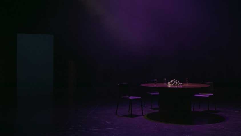 a dark room with an empty roundtable with empty seats